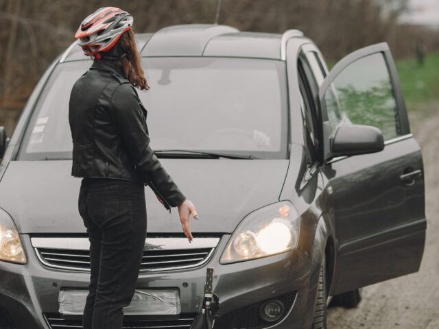 The woman crashed into the car. Girl in a helmet. People quarrel over the accident.